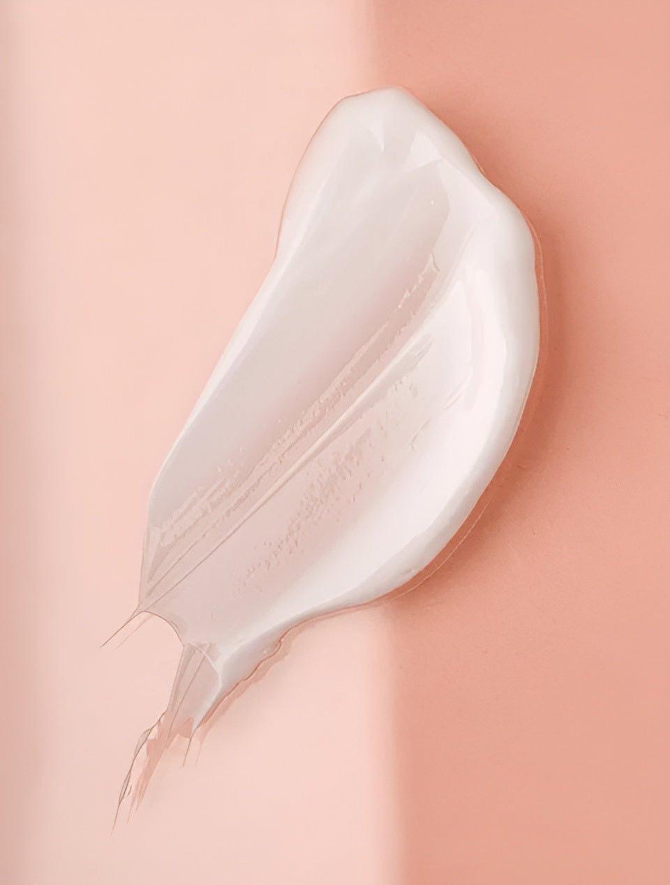 Eclat Soin Collagen Boost Serum swatch showing a smooth, creamy texture on a peach background