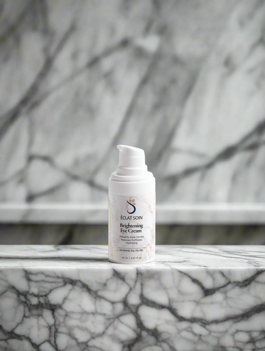 Eclat Soin Puffiness-reducing Brightening Eye Cream in a sleek white bottle on a marble surface